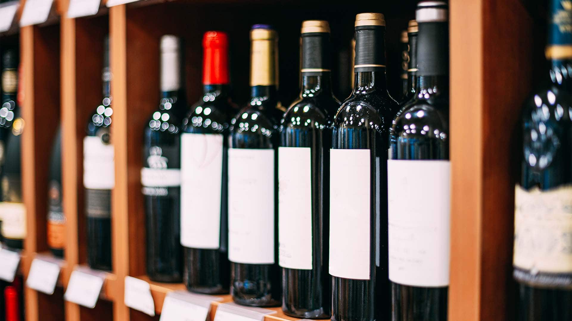 retail shop shelf of unbranded red wine bottles